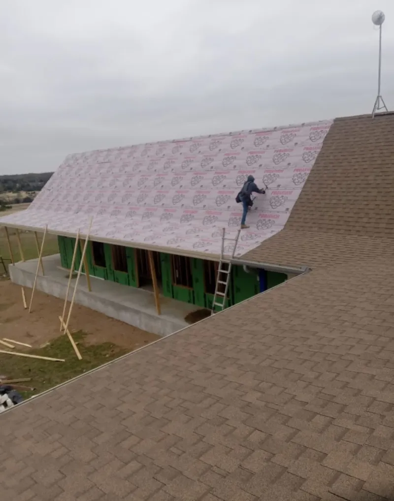 Worker preparing underlayment for a metal roof installation in Houghton